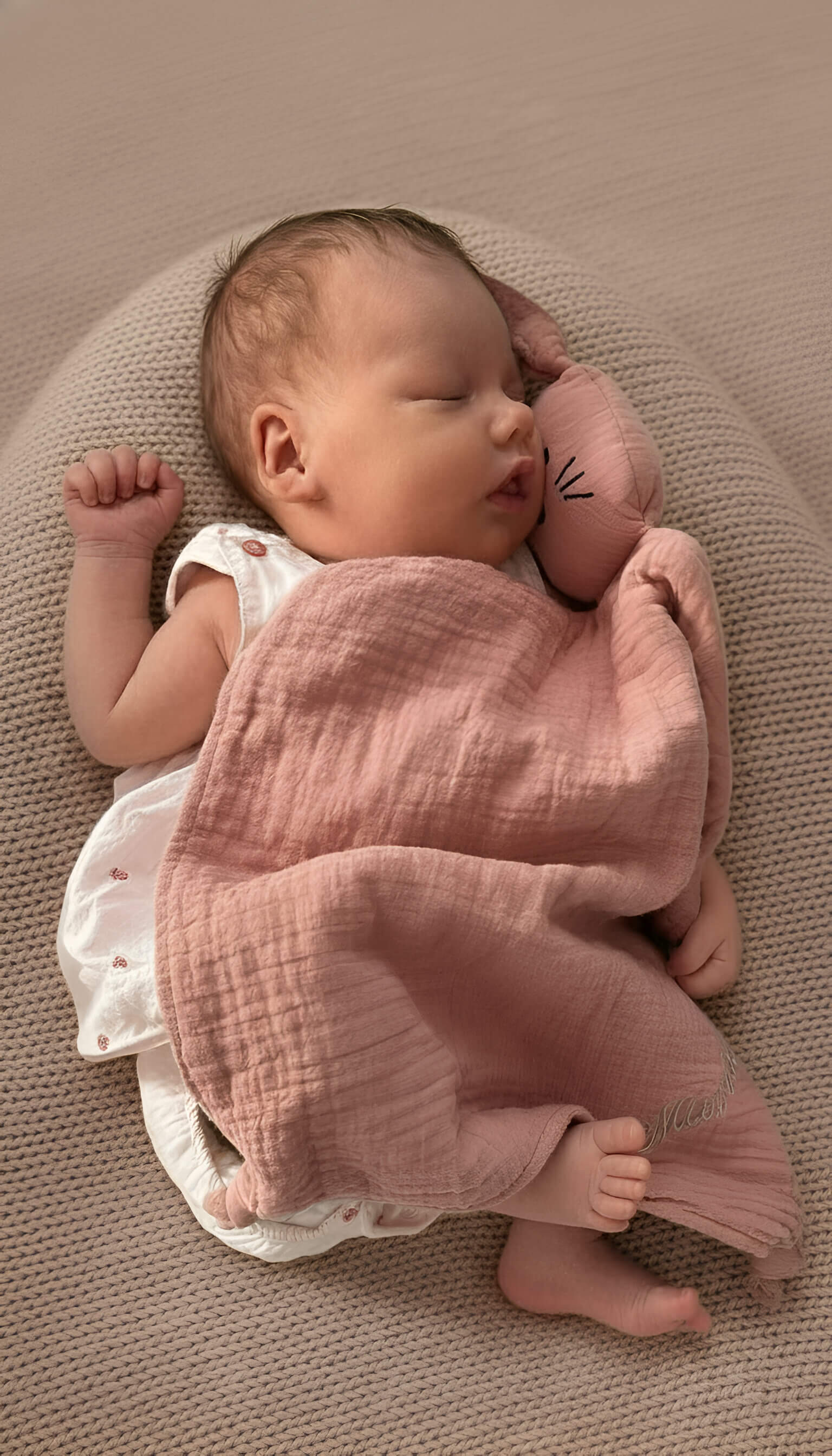 Ein Baby mit Kuscheltuch in rosa personalisiert, das zufrieden schläft.