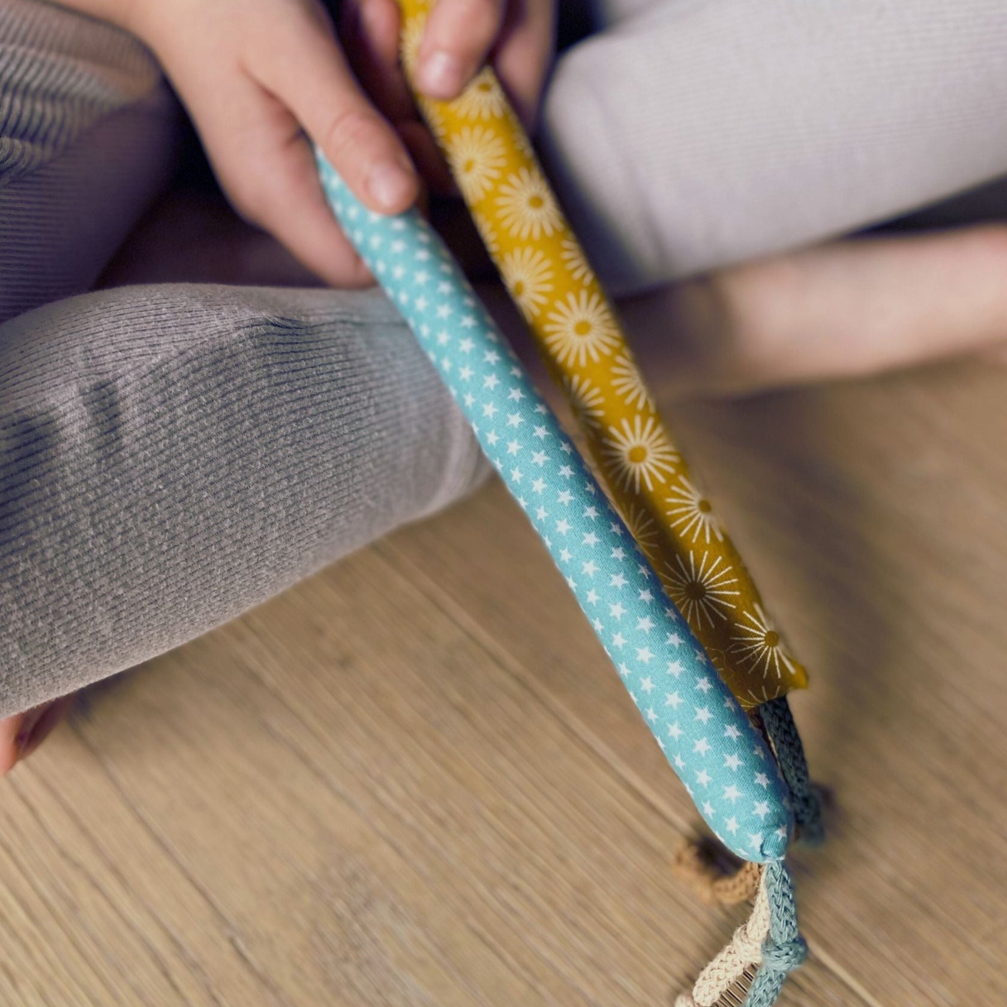 Haende eines Kindes mit einer weichen Baumwoll-Kaustange zur Linderung von Zahnungsschmerzen