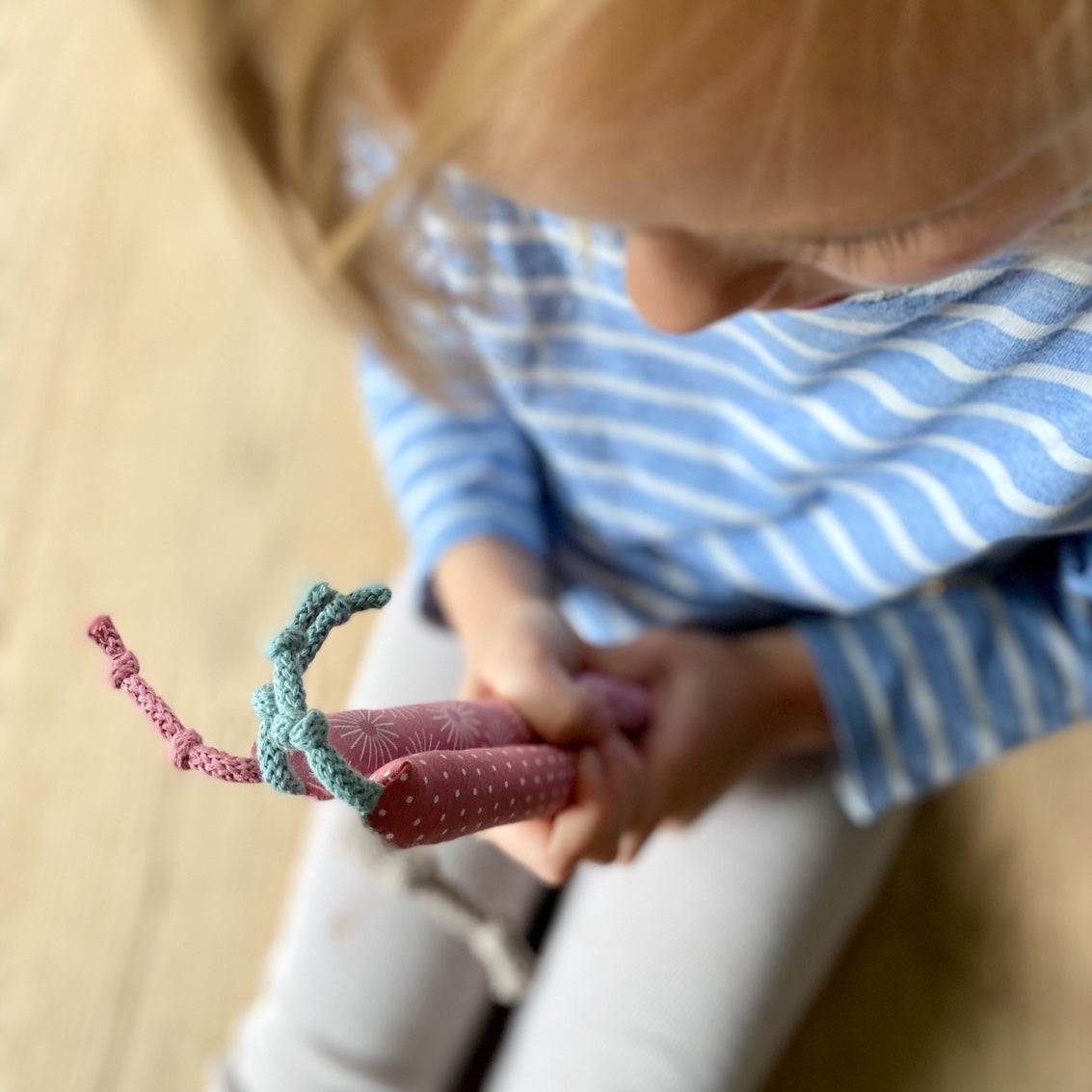 Zufriedenes Baby mit einer weichen Baumwoll-Kaustange zur Linderung von Zahnungsschmerzen.