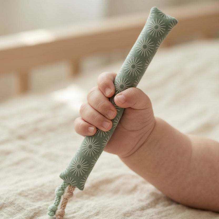 Hand eines Kindes mit einer weichen Baumwoll-Kaustange zur Linderung von Zahnungsschmerzen